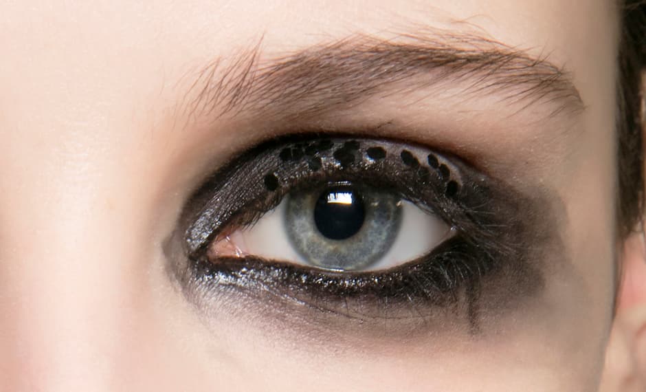 Un maquillaje dramático que tiene un efecto corrido un tanto desaliñado. Incluye pequeñas lentejuelas negras que se integran al maquillaje. Si lo quieres imitar no olvides delinear la línea de agua.
<br>