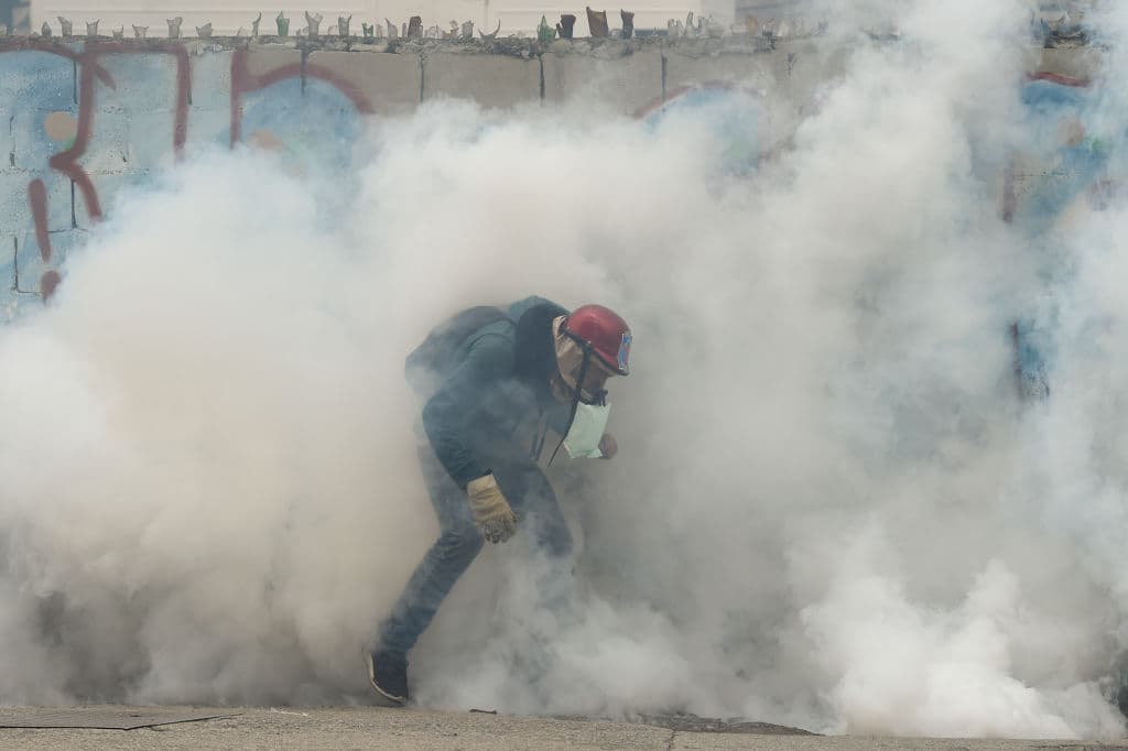 Un opositor cubierto por una nube de gases lacrimógenos durante el enfrentamiento de este jueves con la policía. Hasta el momento, las protestas contra el gobierno de Maduro han dejado 8 personas fallecidas en Venezuela y más de 500 detenidos. Las últimas tres muertes ocurrieron el miércoles: dos jóvenes y un guardia nacional, todos por disparos.