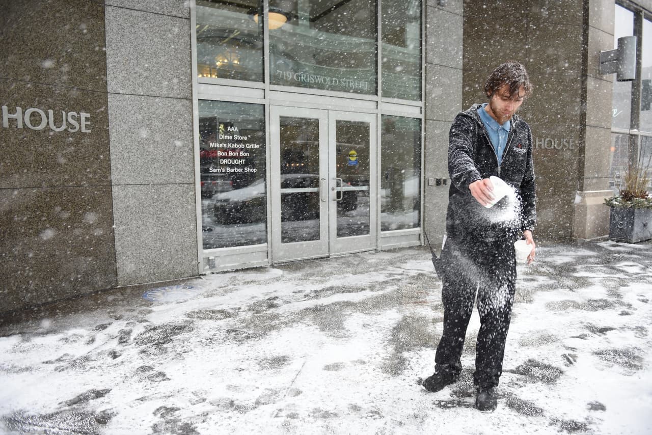Un empleado vierte sal en la entrada de un edificio de oficinas en Detroit
