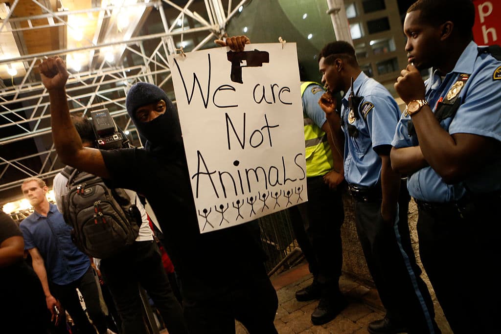 Los manifestantes levantan carteles con frases como "las vidas de los negros importan" y "no somos animales" (la de la foto) durante las protestas por la muerte de un afroamericano a manos de la policía en Charlotte.