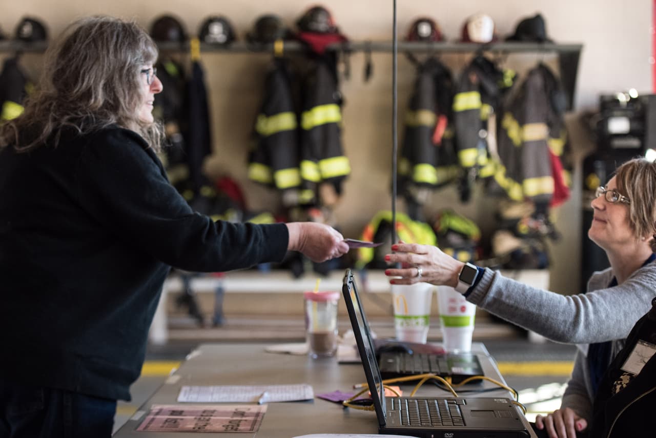 La votante Duna Miller, a la izquierda, con la trabajadora electoral Melissa Moseley, a la derecha, también en la estación de bomberos. (Foto por Sean Raimundo).