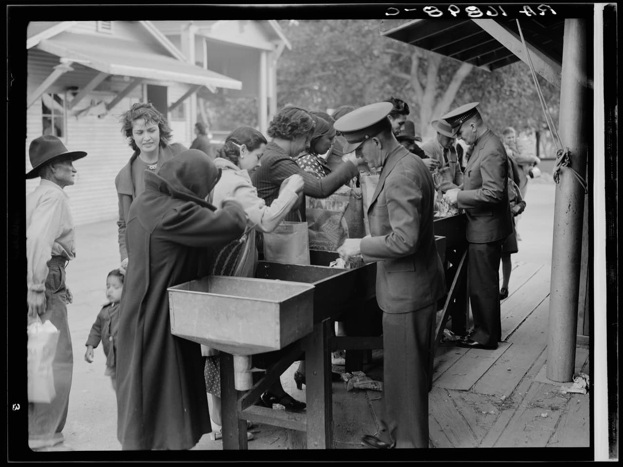 <b>Inspección del departamento de agricultura entre Estados Unidos y México. "</b>Los compradores que regresan de Juárez (México) a El Paso (EEUU) por el puente que transporta todo el tráfico, están obligados a abrir sus paquetes para la inspección". Junio 1937.