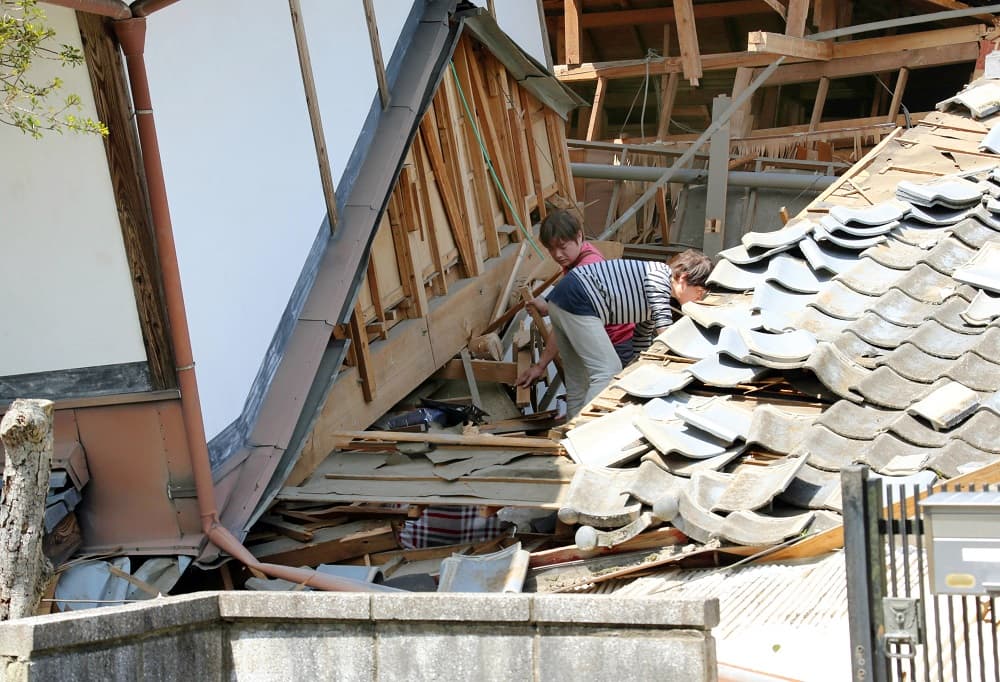 Dos personas tratan de recuperar sus pertenencias de entre los escombros de las casas
