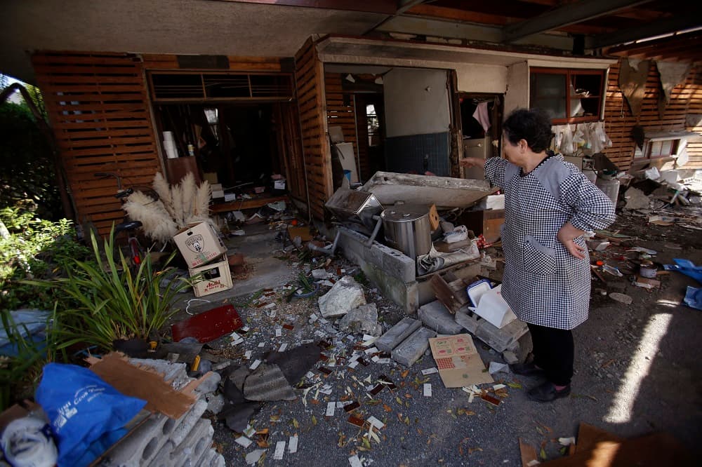 Una mujer frente a lo que quedó de su casa tras el fuerte sismo que golpeó Japón