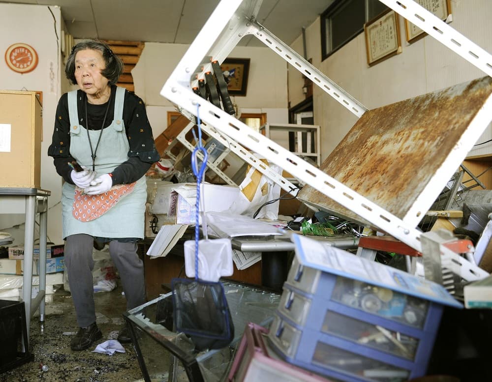 Una mujer trata de limpiar el interior de una tienda afectada por el fuerte temblor