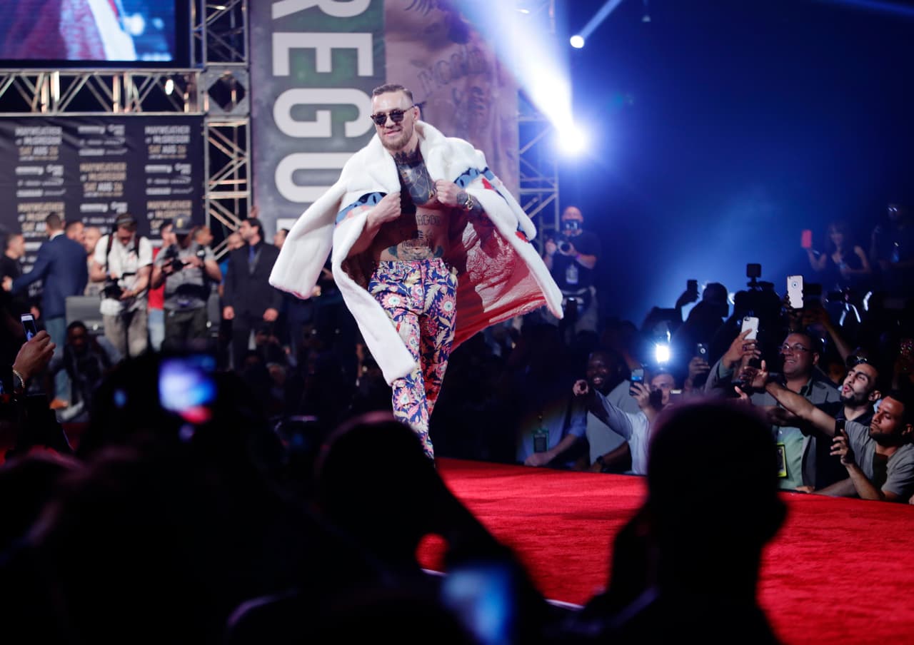 El irlandés, campeón de artes marciales mixtas de la UFC (Ultimate Fighting Championship), apareció en el Barclays Center neoyorquino vestido con un abrigo de piel blanco adornado en la espalda de una enorme serpiente de varias cabezas; su torso, desnudo, exhibió numerosos tatuajes entre ellos el de su nombre.
