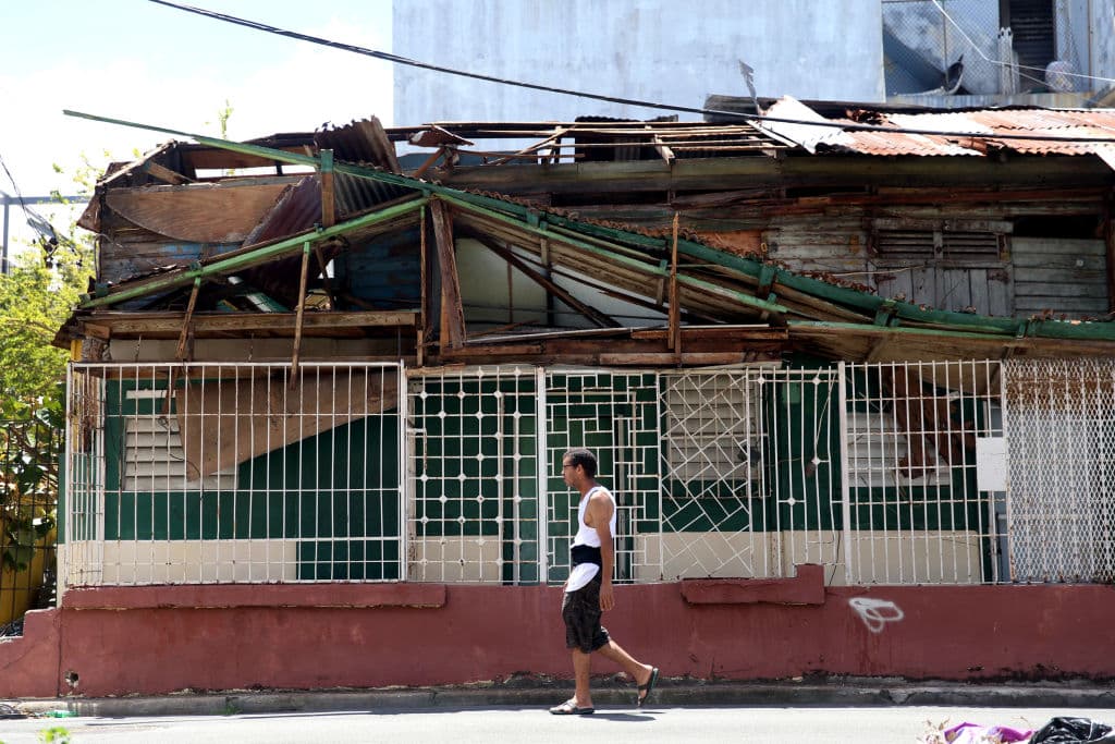 Un hombre camina frente a una casa afectada por el huracán en San Juan, Puerto Rico.