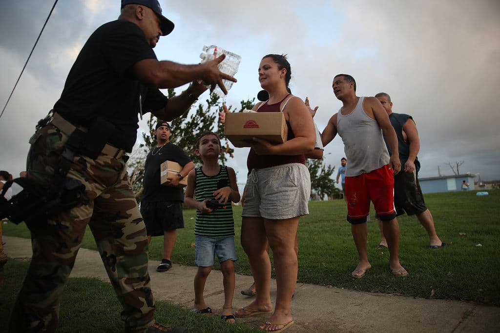 El sargento de la policía municipal Nelson Sierra entre comida y agua a residentes afectados por el huracán María en Toa Baja, Puerto Rico.