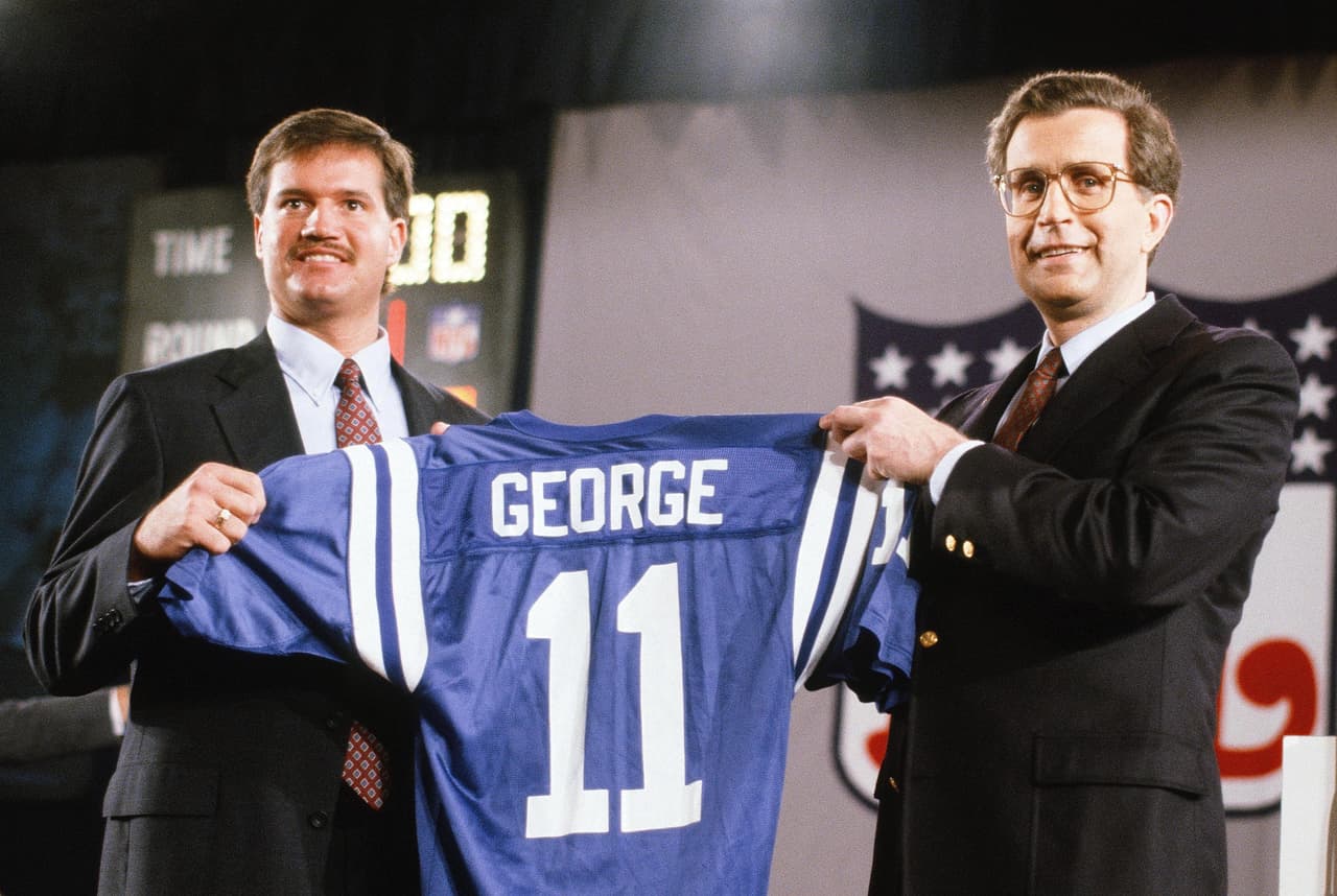 1990 — JEFF GEORGE
<b>Indianapolis Colts</b> | QB Illinois
<br>Seleccionado número 1 global, el mariscal de campo de los Indianapolis Colts, Jeff George (11), sostiene su nueva camiseta de equipo mientras posa para una foto con el comisionado de la NFL, Paul Tagliabue, en el Draft de la NFL el 22 de abril de 1990 en Nueva York. (Paul Spinelli vía AP)