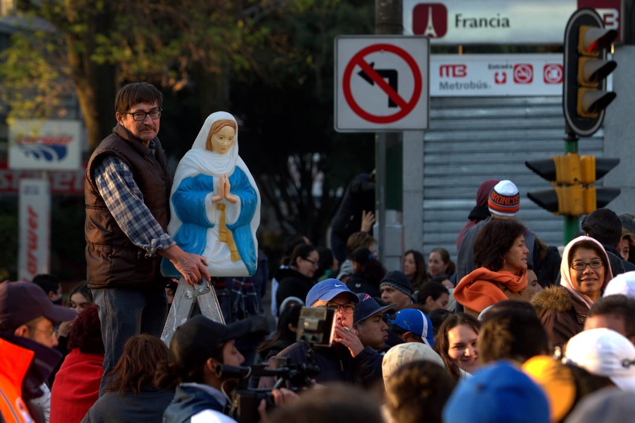Este hombre sostiene una escultura de la Virgen al paso del papa Francisco a la salida de la Nunciatura este domingo.