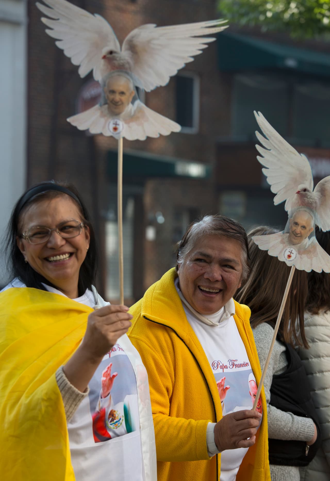Estas dos mujeres sostienen unas palomas, hechas de cartón, con el rostro del papa Francisco.