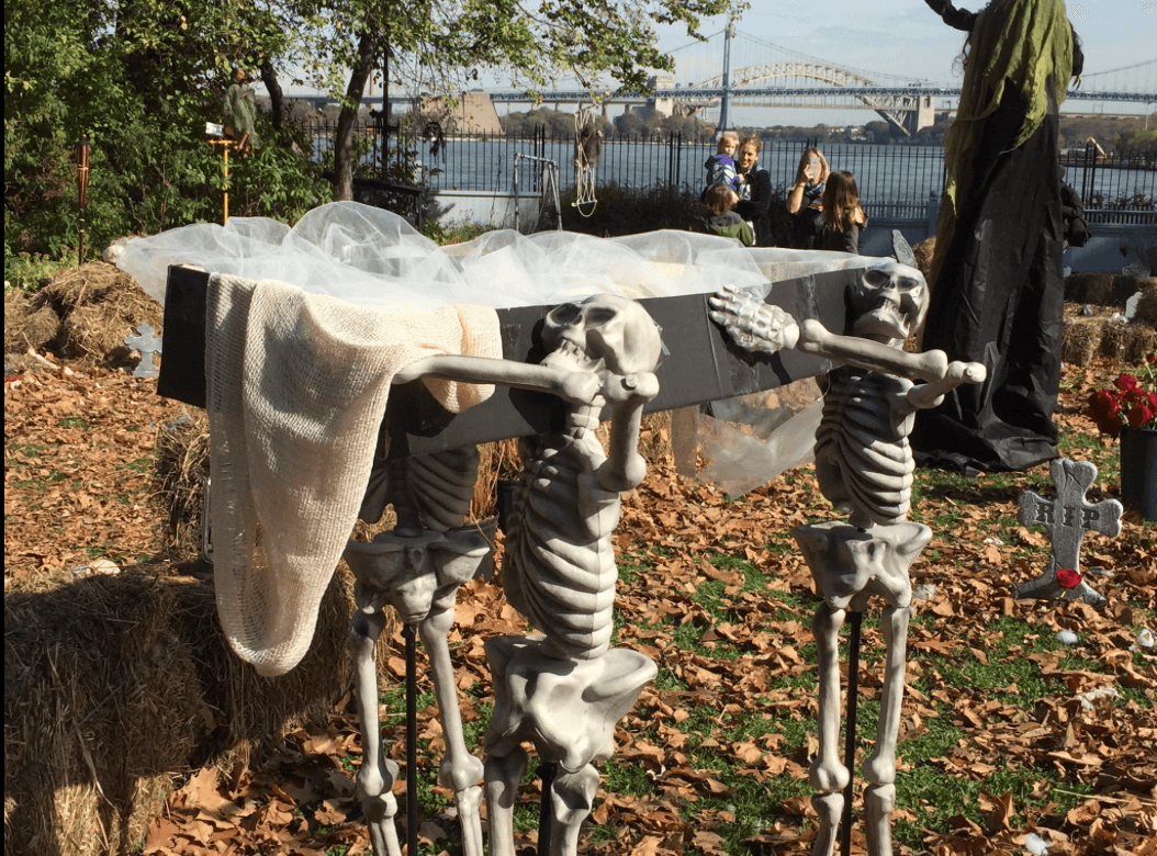 De lejitos algunos observaban a los esqueletos que cargaban un ataúd como parte de la decoración de un recorrido "de terror".