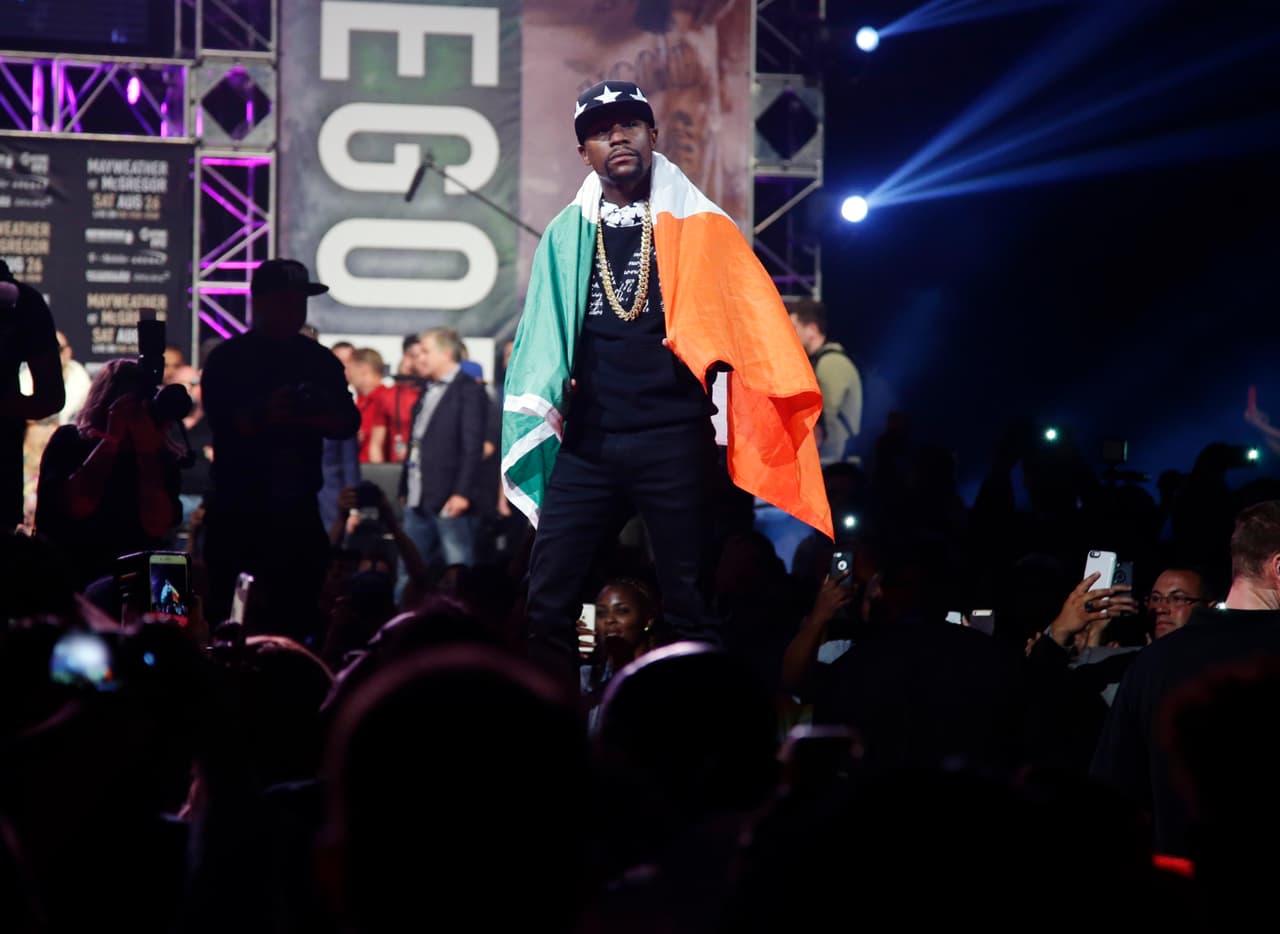 Mayweather se acercó al publico, pidió una bandera de Irlanda, se la puso en la espalda y empezó a caminar como McGregor, para después hincarse durante casi un minuto mientras miraba a su rival.