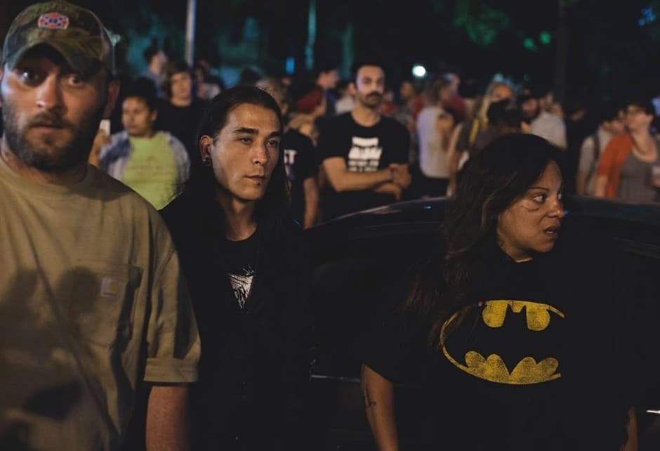Los partidarios de los monumentos confederados reaccionan al ser acompañados lejos del lugar, mientras la policía los dirige a sus vehículos.