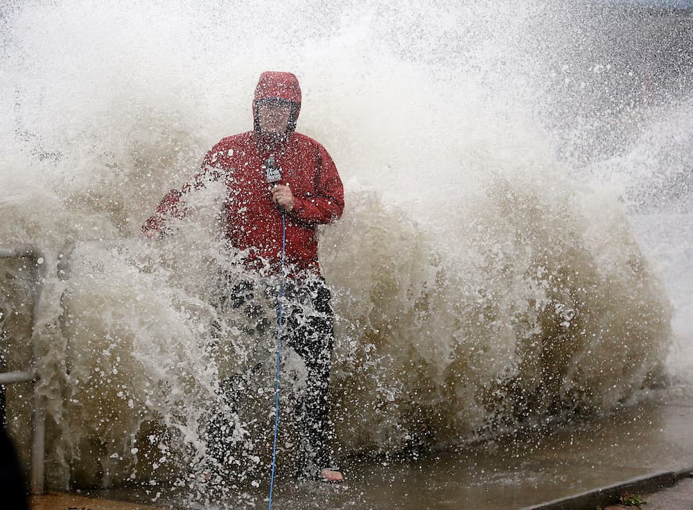Este reportero con impermeable informa sobre la llegada del temporal desde un malecón en Cedar Key