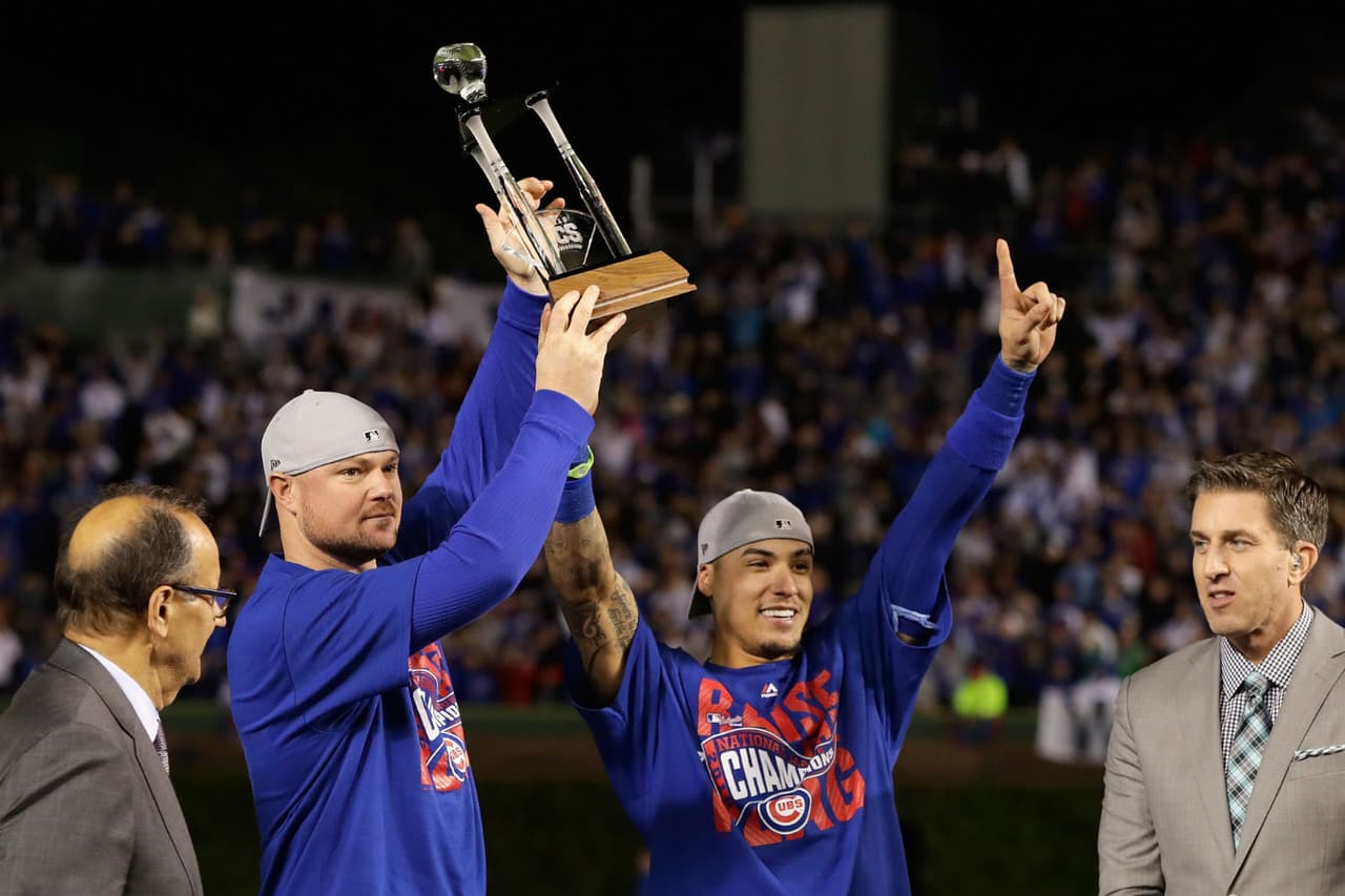 Jon Lester y Javy Baez sostienen el trofeo que tardaron 71 años en volver a levantar.