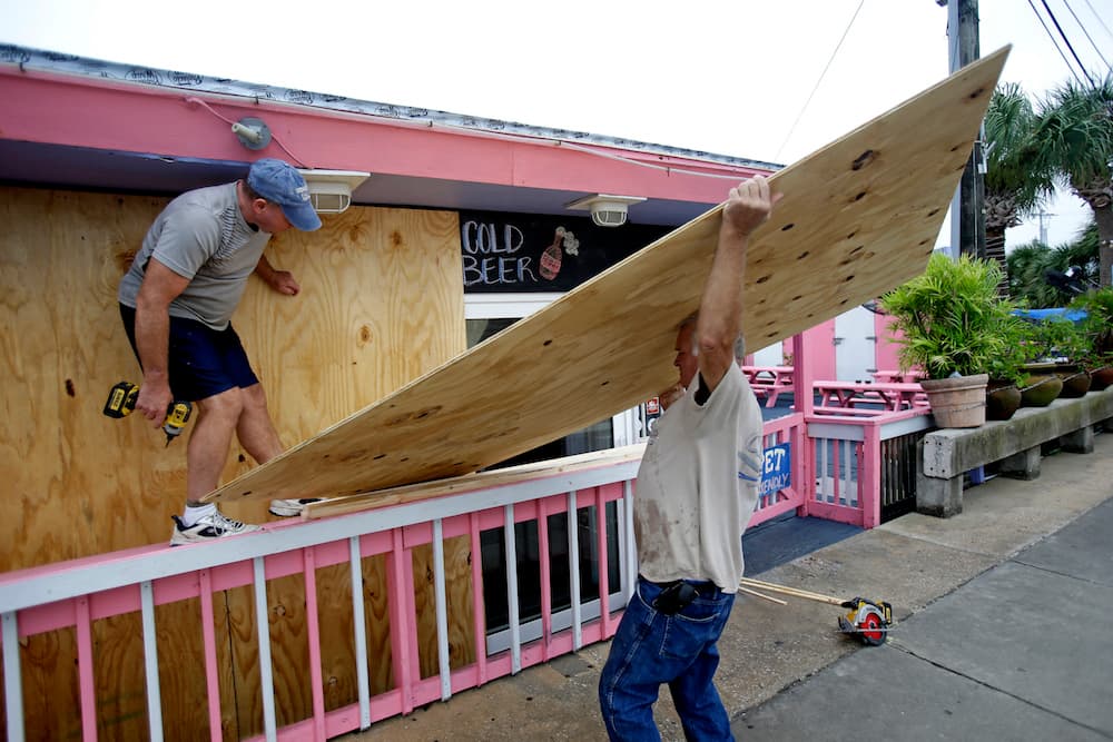 Dos hombres protegen con maderas las ventanas de este bar en Cedar Key, ante la llegada del huracán Hermine