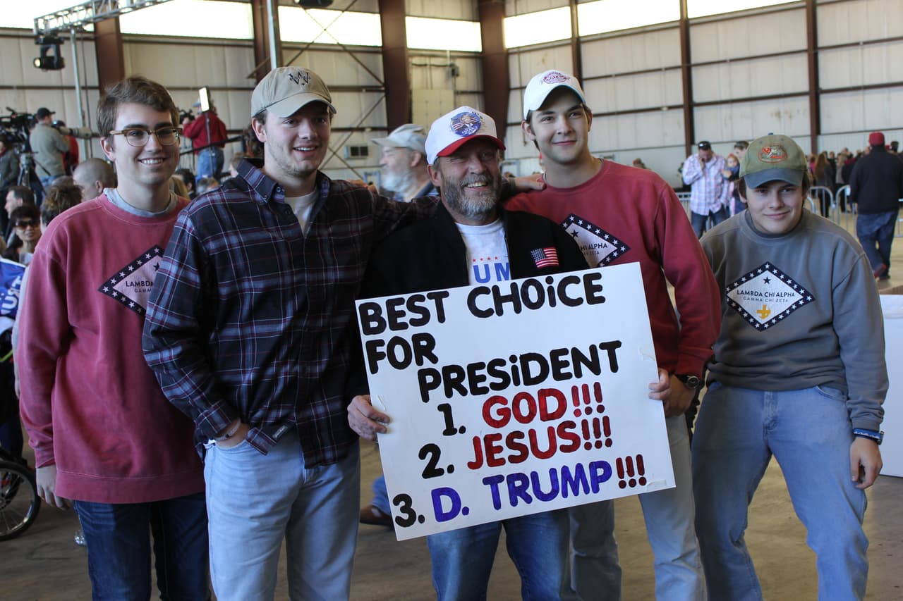 Unos jóvenes piden una foto a Steven, en el centro, antes de la llegada de Trump
