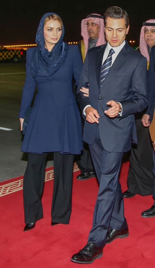 Cubriendo su rostro con un velo.