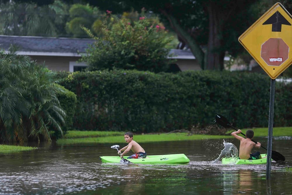 Unos niños navegan por un barrio inundado de St. Petersburg, Florida, por el paso del huracán Hermine.