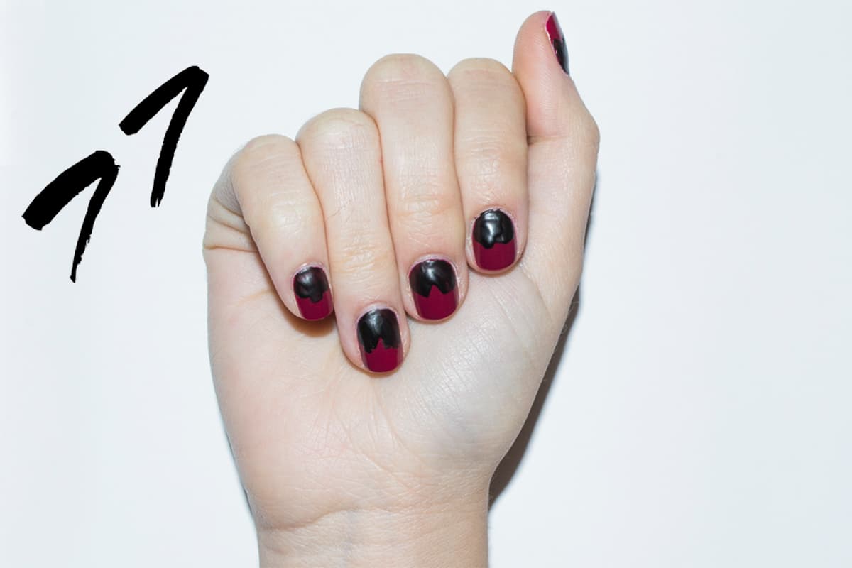 Aplica dos capas de un esmalte color vino. Después con un color negro mate da brochazos de forma desigual, de la cutícula a la mitad de la uña.