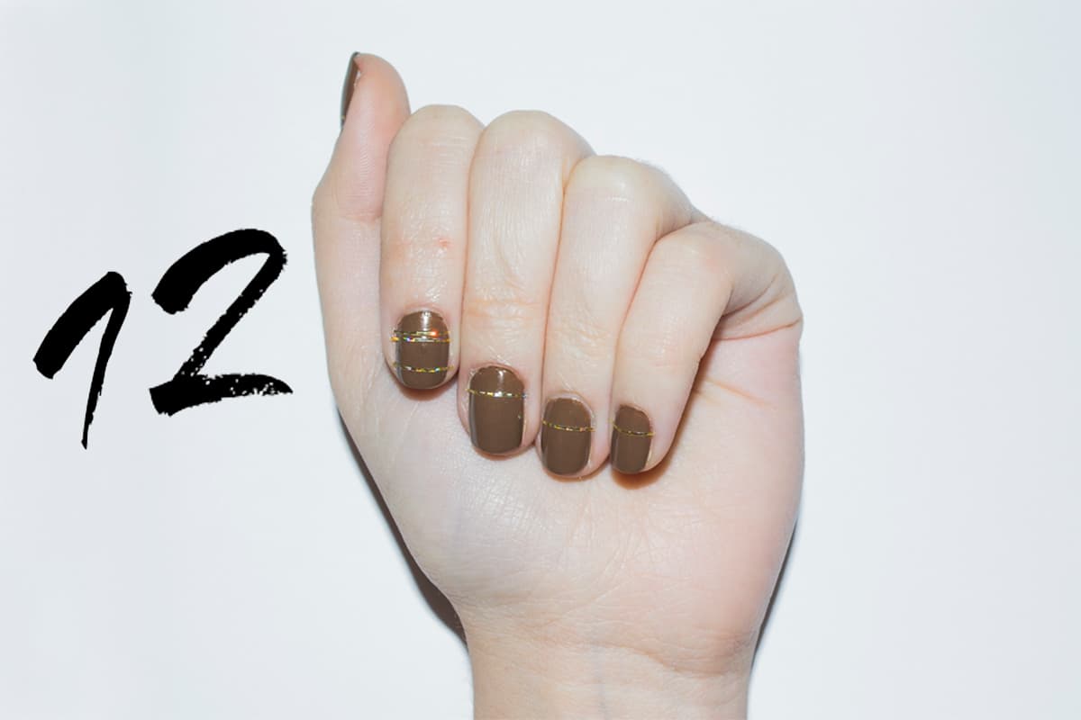 Da dos capas de un tono café, deja secar. Decora con cintilla dorada o plateada trazando una línea vertical en la parte superior de la uña. Para que quede fija, no olvides sellar con la capa de brillo.