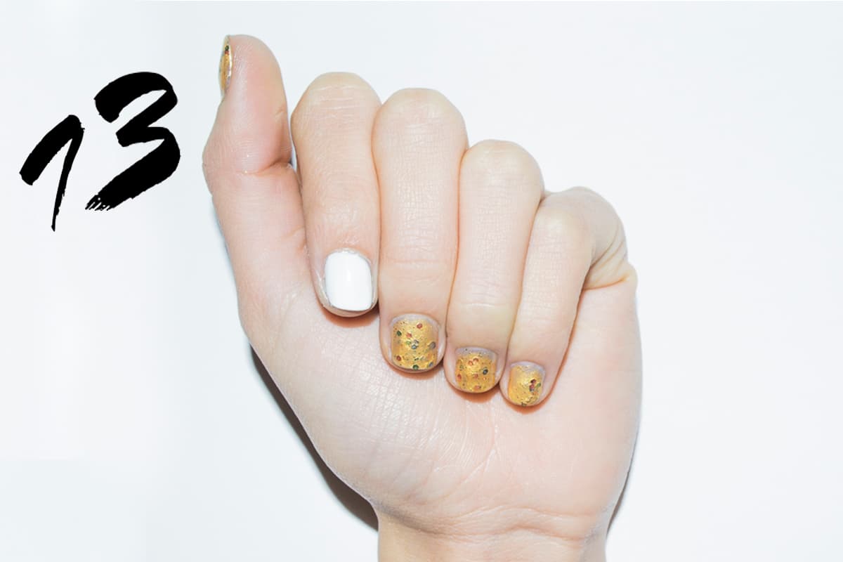 Aplica dos capas de esmalte blanco en el dedo índice. En el resto de las uñas aplica dos capas de esmalte dorado brillante. Cuando la segunda capa este fresca aplica puntitos de diferentes colores en la superficie.