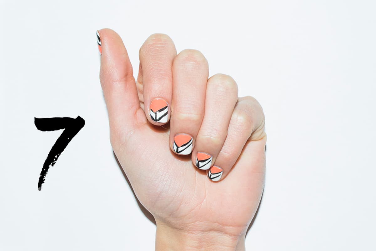 Deja secar dos capas de esmalte blanco. Con un pincel delgado traza dos líneas formando una V en la parte superior de la uña. En la unión de las dos líneas traza una línea vertical hacia la punta y otra paralela a la línea que forma la V. Con un palillo rellena con un color de tu elección el espacio en blanco.