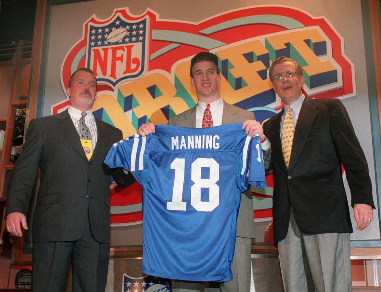 1998 — PEYTON MANNING
<b>Indianapolis Colts</b> | QB Tennessee
<br>El quarterback Peyton Manning sostiene el jersey de los Indianapolis Colts mientras está flanqueado por el propietario de los Colts, Jim Irsay (izquierda) y el comisionado de la NFL, Paul Tagliabue, el sábado 18 de abril de 1998 en Nueva York después de ser elegido por los Potros como la selección N° 1 del draft. (Foto AP / Adam Nadel)