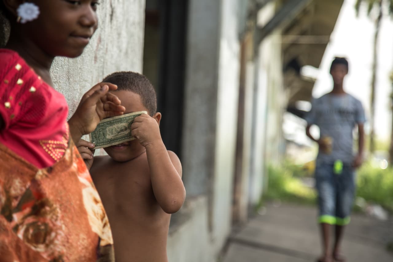 Dos niños juegan con lo que encuentran. En medio de la pobreza, chapotean en el agua que inunda la calle o patean las latas que lanzan los vecinos.
