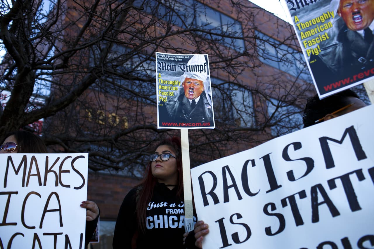 El precandidato republicano Donald Trump suspendió un evento este viernes en la Universidad de Illinois, Chicago, debido a las protestas de grupos opositores. En la imagen, una mujer muestra una pancarta en la que lo tilda de fascista.