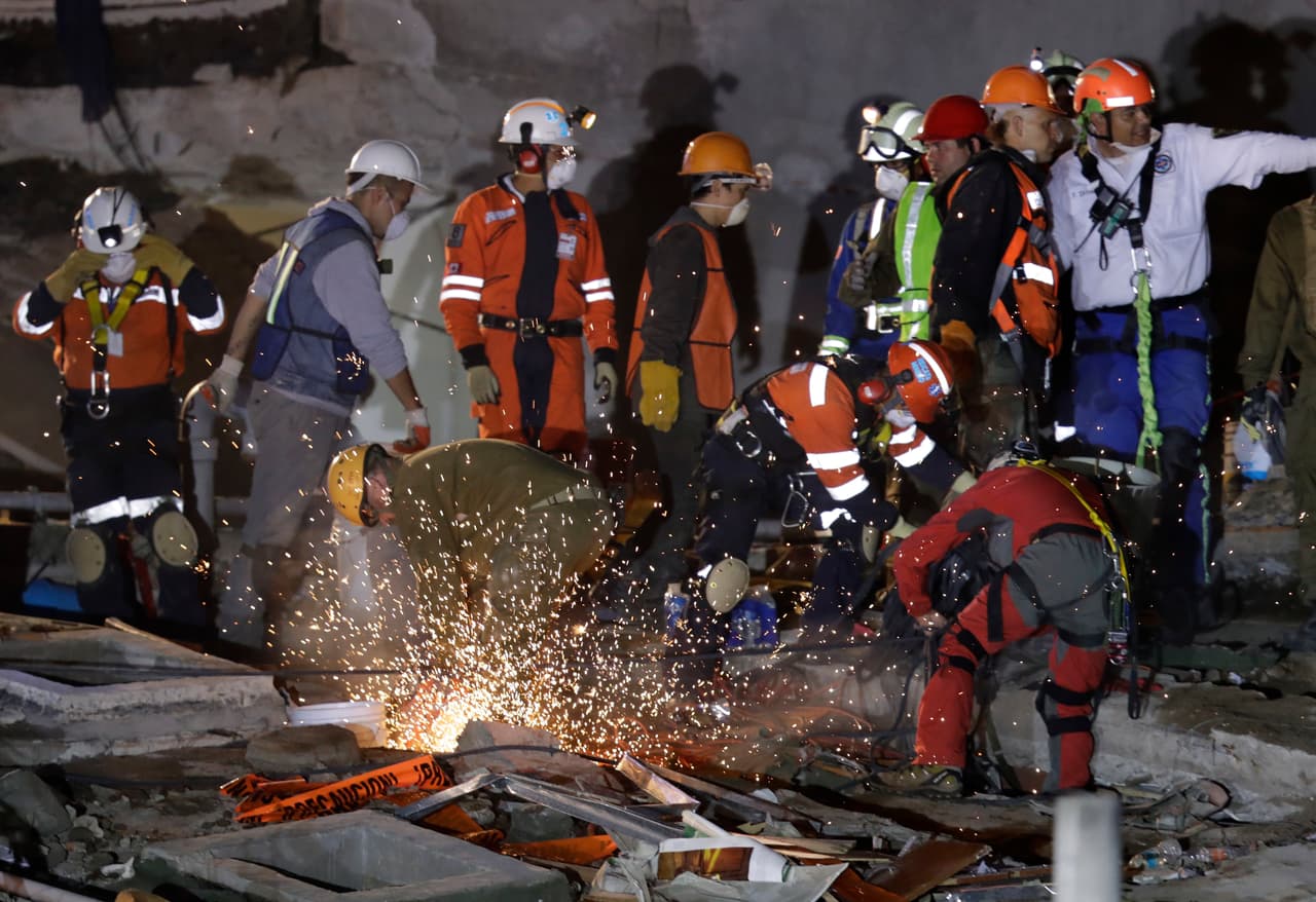 Rescuers race against the clock to reach possible survivors trapped inside an office building in the Roma Norte neighborhood of Mexico City, in the early morning hours of Saturday, Sept. 23, 2017. A strong earthquake Tuesday toppled more than three dozen buildings in the capital, leaving dozens of people believed missing in this office building alone. (AP Photo/Rebecca Blackwell)