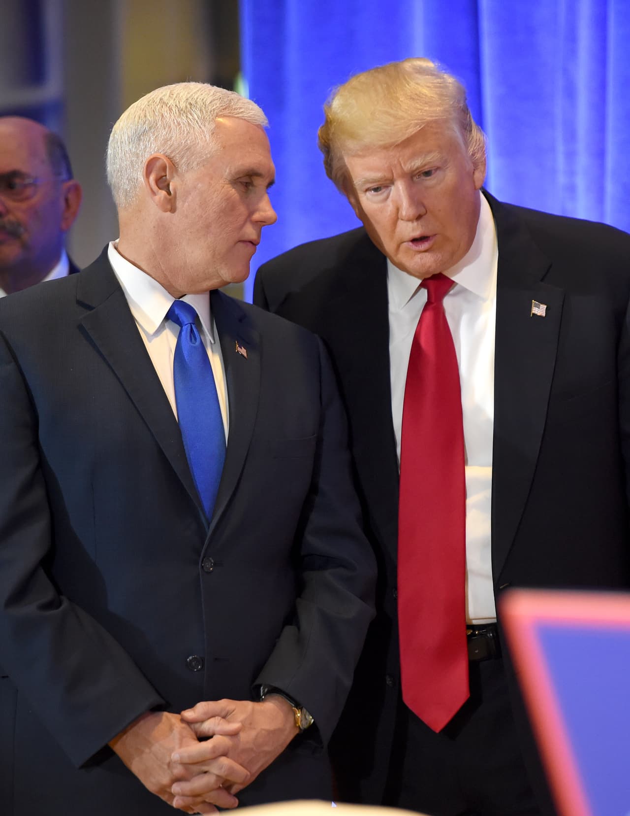 Donald Trump escucha a Mike Pence, instantes antes de comenzar la conferencia.