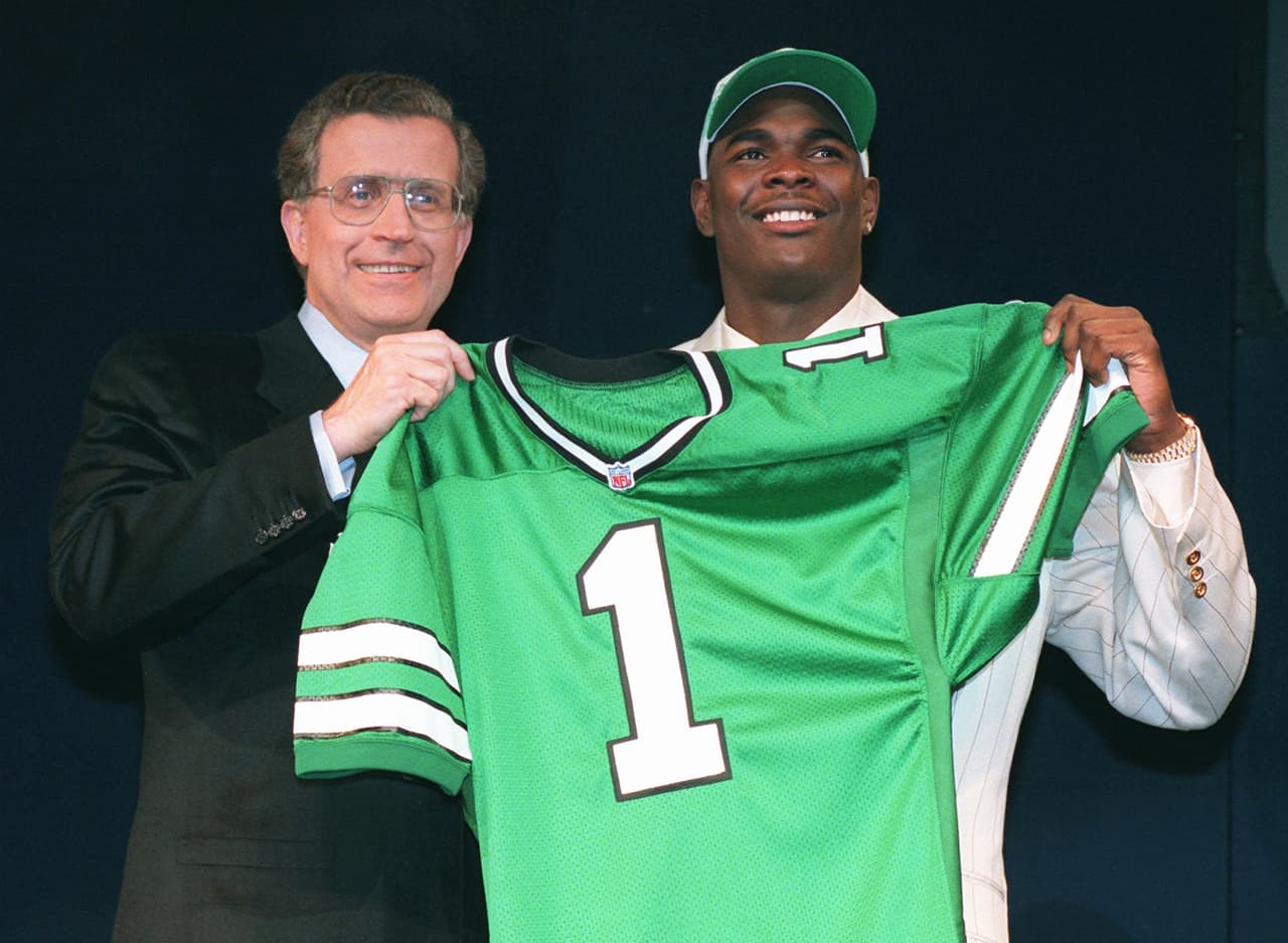 1996 — KEYSHAWN JOHNSON
<b>New York Jets</b> | WR Southern Cal
<br>El receptor abierto Keyshawn Johnson de la Universidad del Sur de California, posa con el jersey de los Jets con el comisionado de la NFL, Paul Tagliabue, después de ser tomado por los New York Jets como la primera selección en el draft el sábado 20 de abril de 1996 en Nueva York. (Foto de AP / Wally Santana)