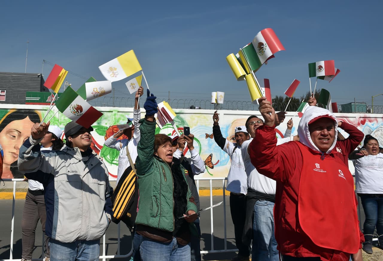 Un grupo de fieles agitan sus banderas cuando ven pasar al papa Francisco rumbo a Ecatepec.