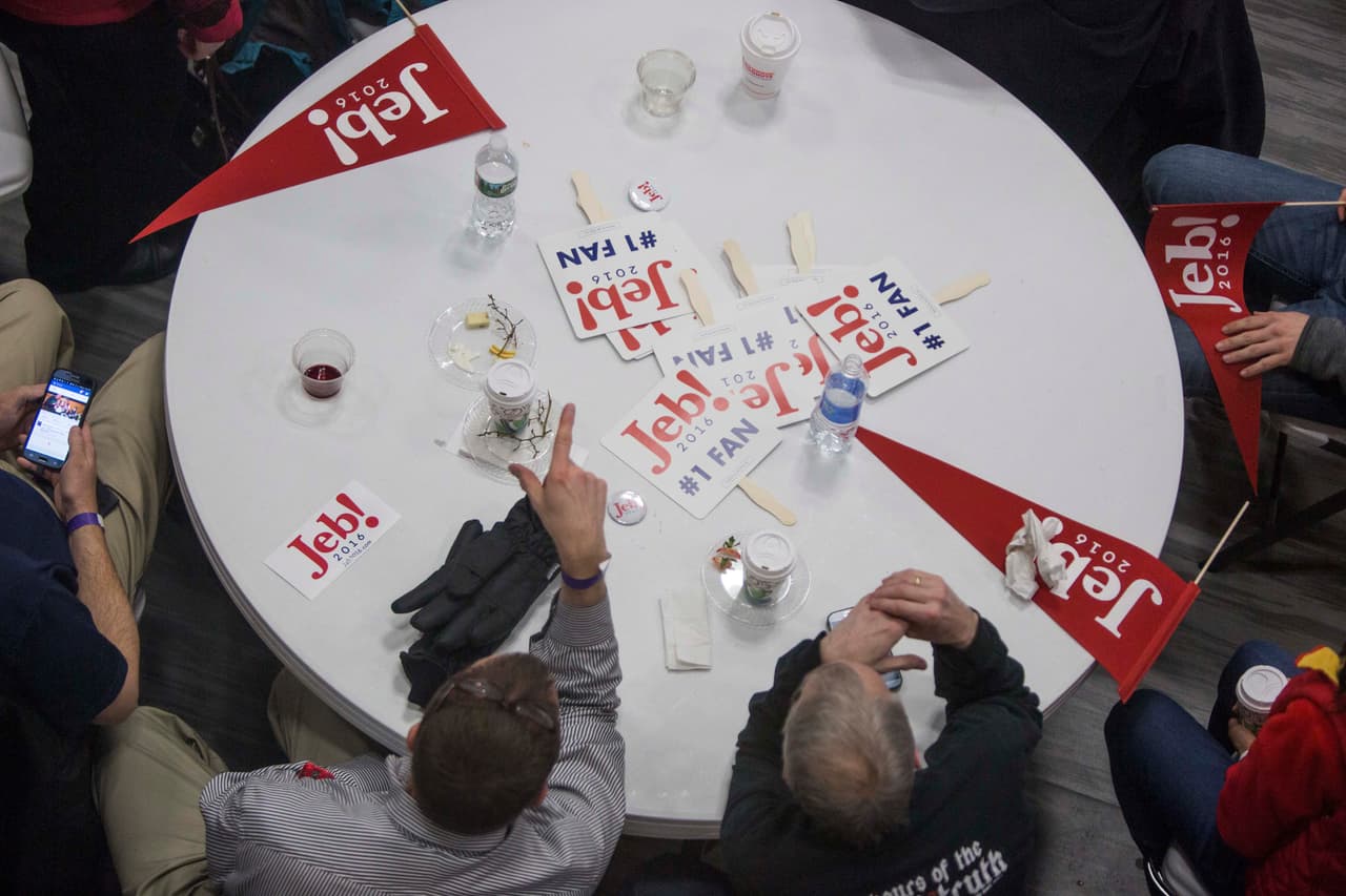 Partidarios del republicano Jeb Bush en una mesa con algunos banderines de la campaña