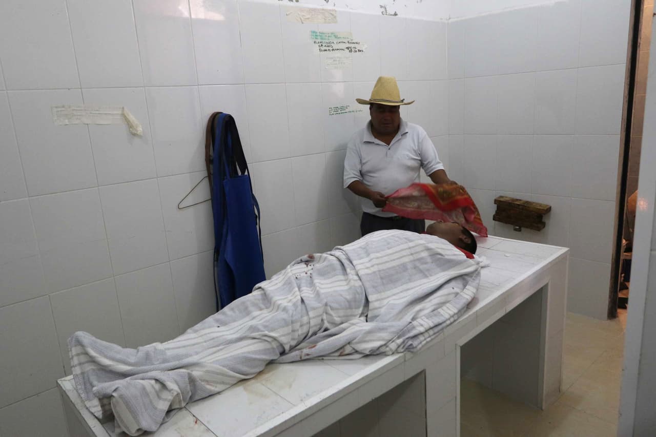 Un hombre se coloca al lado de una de las personas fallecidas durante los enfrentamientos