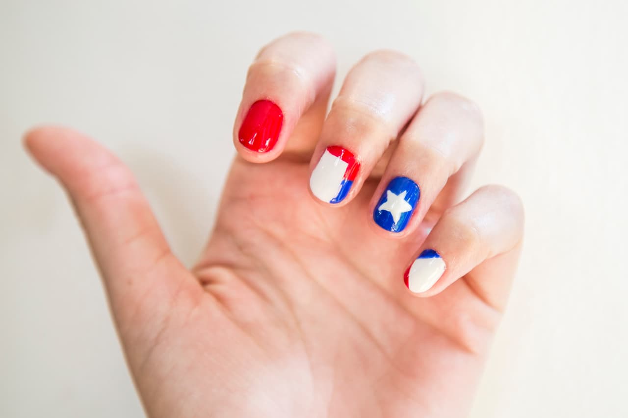 Chile: Aplica 2 capas de barniz blanco en la uñas del dedos medio y meñique, 2 capas azules en anular y 2 capas rojas en dedo índice. Dibuja la estrella con un palillo y rellénala con un pincel muy delgado. En la uña del dedo meñique esmalta con un pincel mediano la esquina superior en azul y la inferior en rojo. En la uña del dedo medio traza una franja horizontal en rojo cubriendo la lúnula y otra vertical mitad roja y mitad azul.