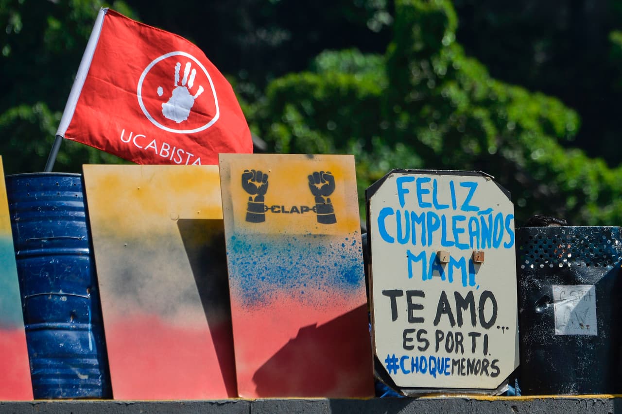 Los activistas de la oposición se protegieron con escudos improvisados durante los enfrentamientos con la policía antidisturbios mientras bloquean la carretera Francisco Fajardo en Caracas.