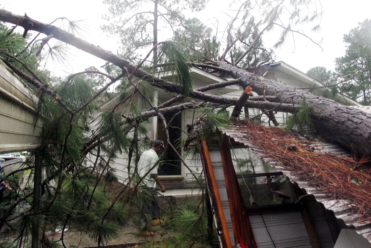 Melvin Gatlin Jr inspecciona la casa de su padre en Valdosta, Georgia, donde un árbol cayó sobre el techo empujado por la fuerza del viento.