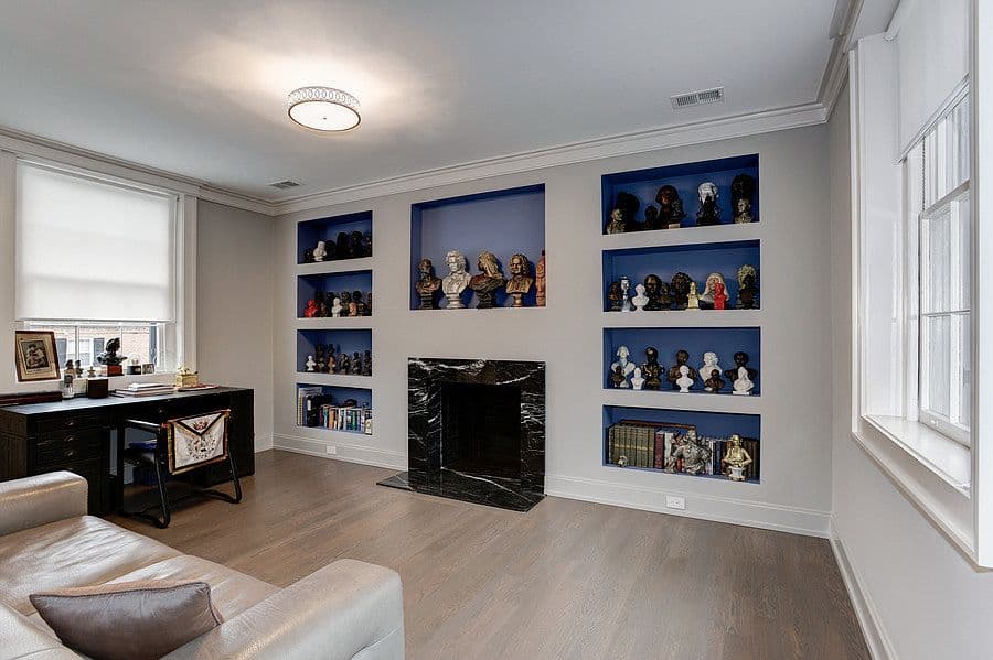 Librería de obra con otra chimenea de mármol en un despacho de la casa.