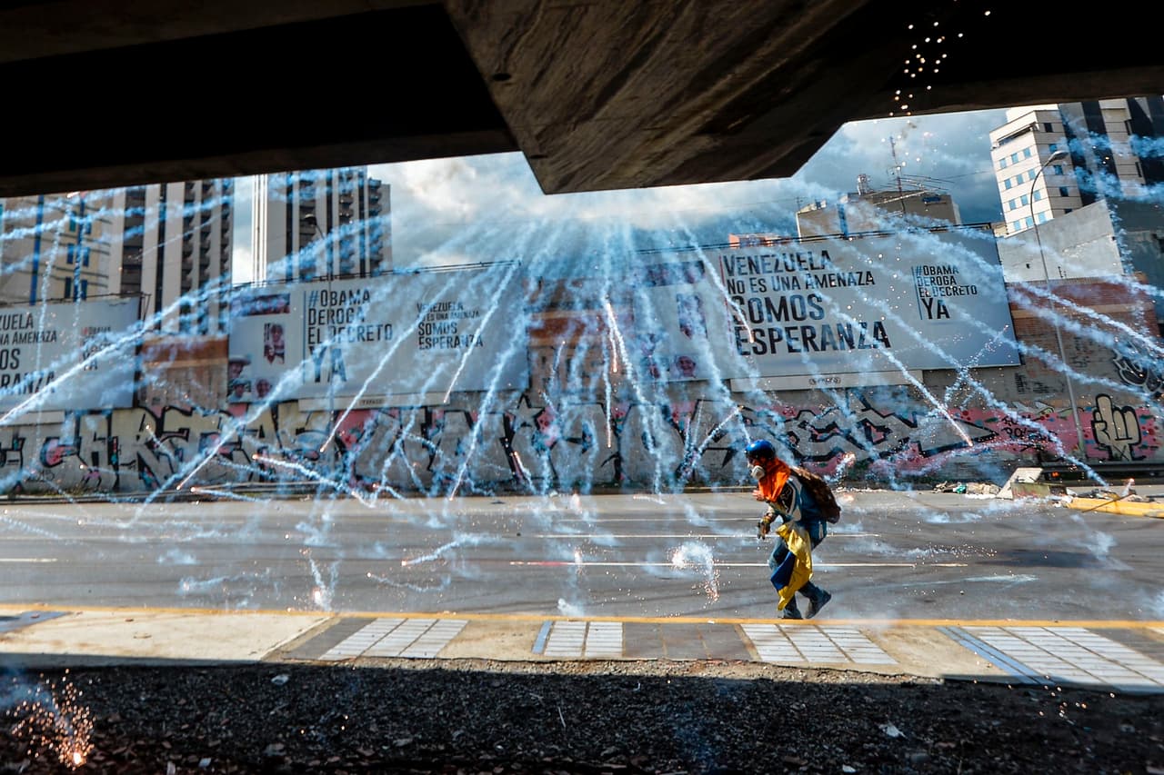 Un manifestante en medio de una lluvia de bombas de gases lacrimógenos.
