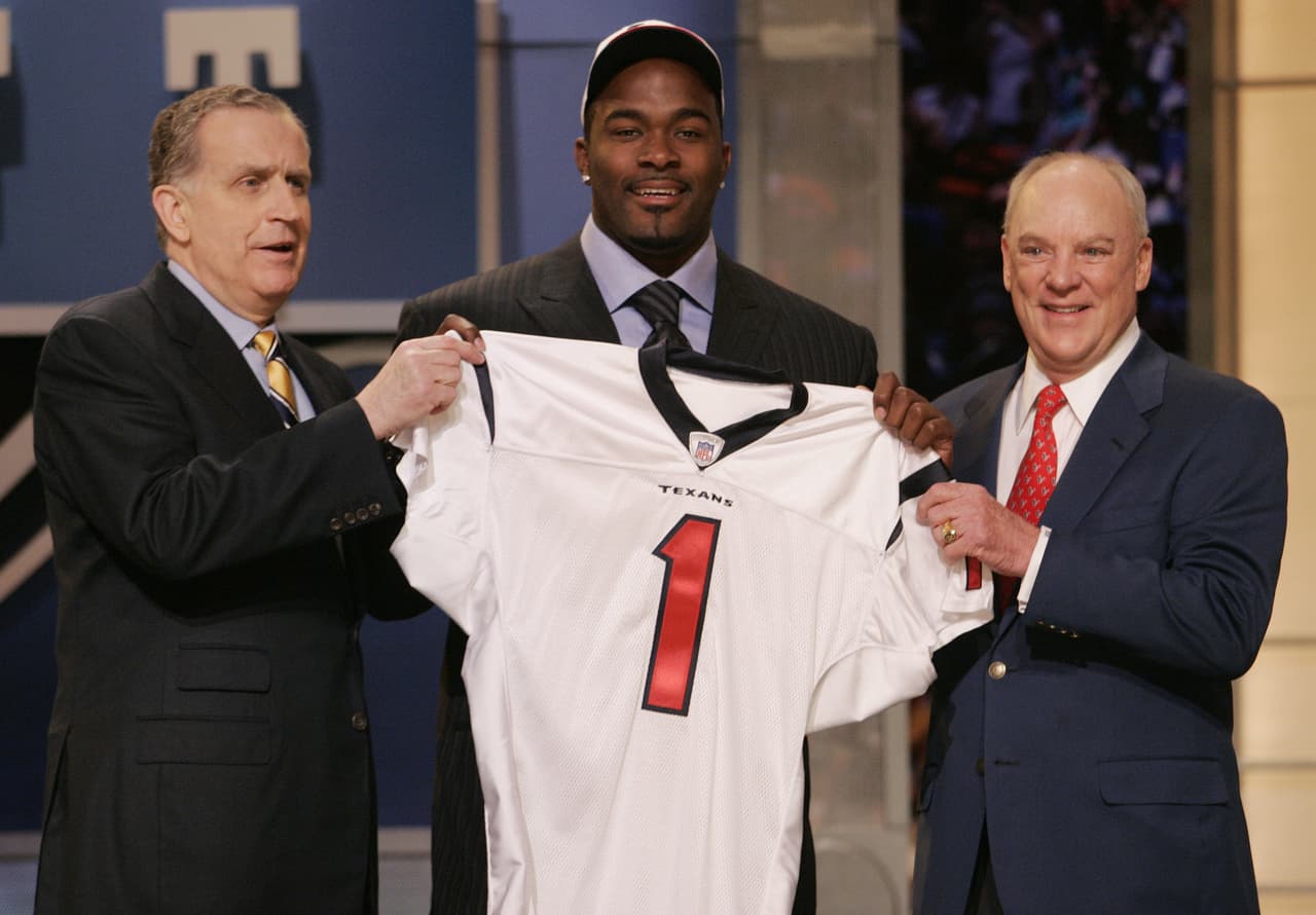 2006 — MARIO WILLIAMS
<b>Houston Texans</b> | DE North Carolina State
<br>El ala defensiva, Mario Williams (centro) de Carolina del Norte, sostiene una camiseta de los Houston Texans junto al comisionado de la NFL, Paul Tagliabue, (izquierda) y el dueño de los Texans, Robert McNair, después de ser elegido como la selección número 1 en el Draft, el 29 de abril de 2006 en el Radio City Music Hall de Nueva York. (AP Foto / Ed Betz)