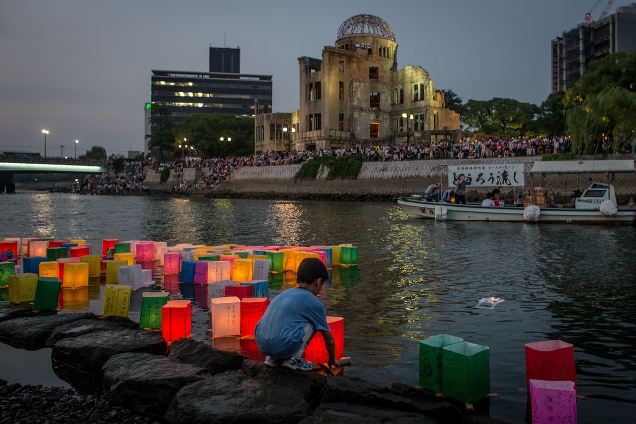 Un niño coloca una linterna hecha con velas y papel sobre el río en frente del “Domo de la bomba Atómica”, como parte de las actividades del 70 aniversario de la tragedia en el Parque conmemorativo de la Paz de Hiroshima 6 de agosto de 2015.
