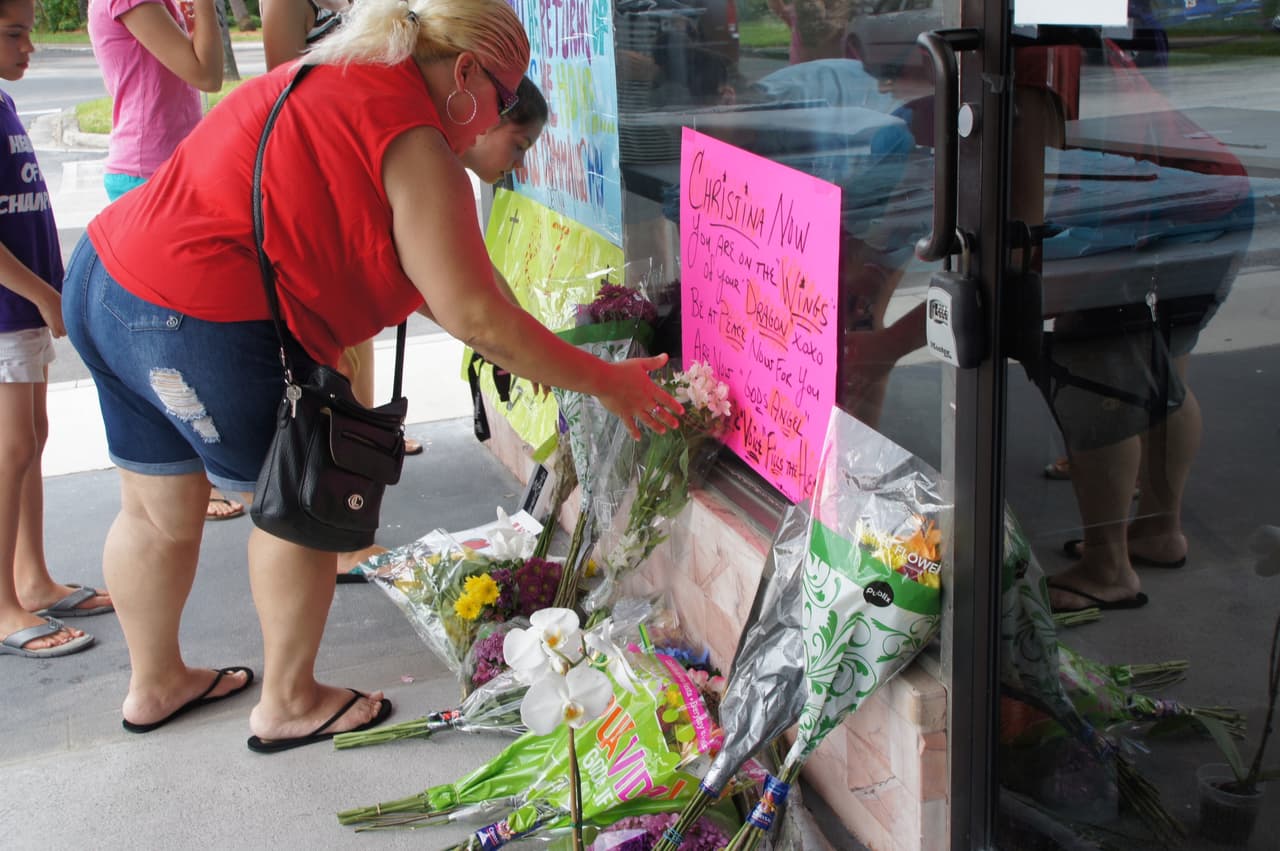 Mujeres depositan flores en la entrada del lugar en memoria de Christina