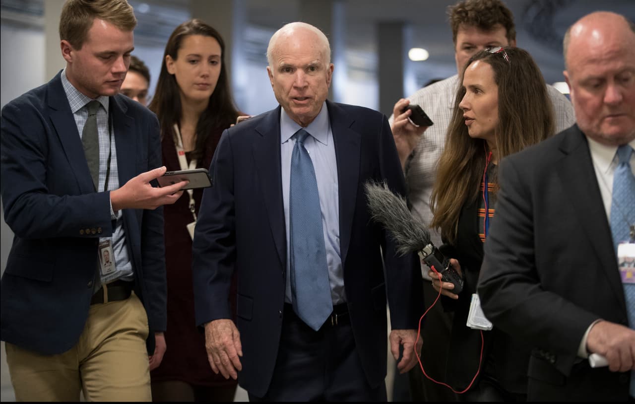 El senador John McCain rodeado de reporteros.