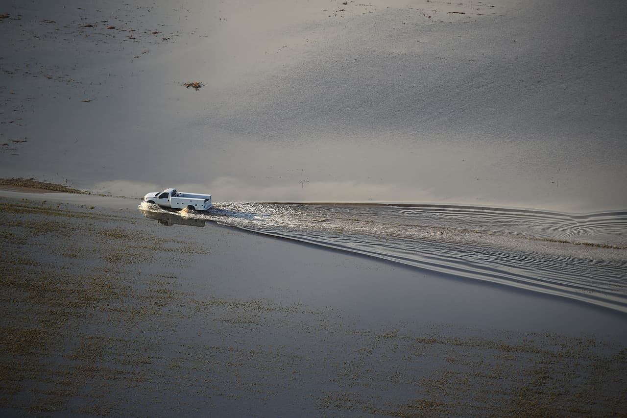 Una camioneta avanza como si fuera una lancha, a través de un campo inundado en el área agrícola de Homestead.