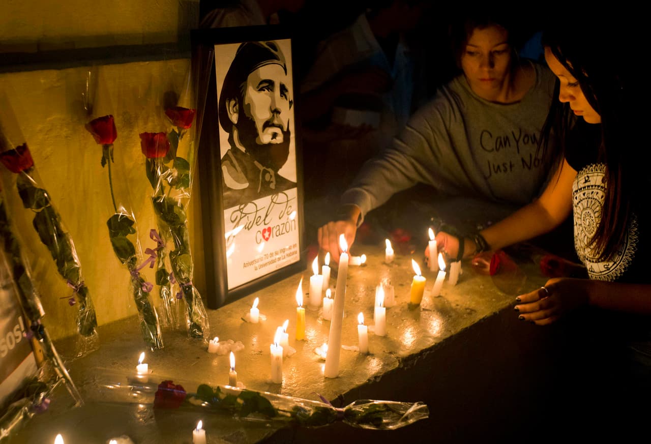 Un grupo de estudiantes colocan velas a la imagen de Fidel Castro durante una vigilia en La Habana.