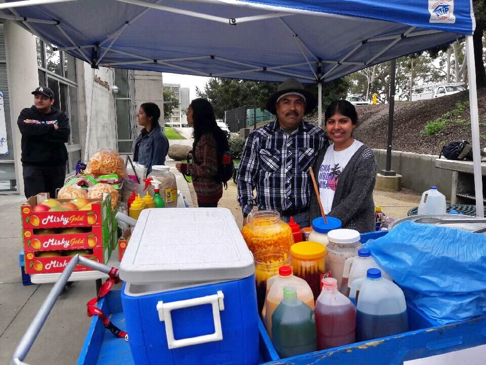 El elotero Hijinio Camacho posa en una fotografía con una estudiante de la Universidad de California en Santa Barbara (UCSB), donde vende sus productos y acepta pagos electrónicos.