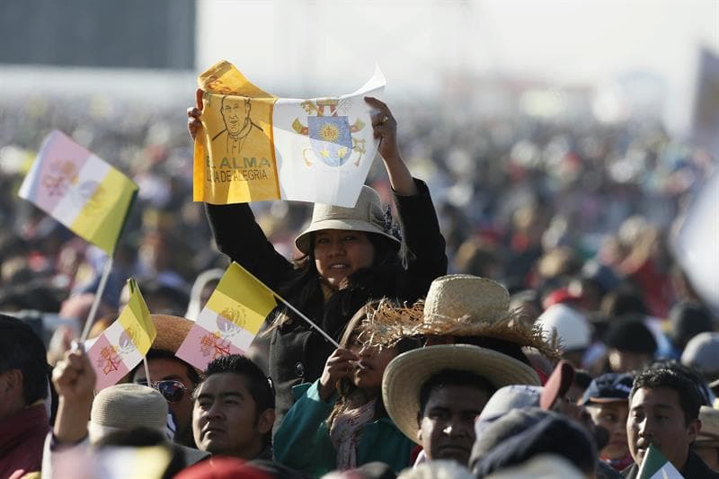 En Ecatepec, miles de fieles, celebran la Santa Misa con el papa Francisco. Un cártel y banderas con los colores del Vaticano.